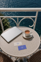 Business card mockup PSD on a balcony table overlooking the sea with an espresso cup
