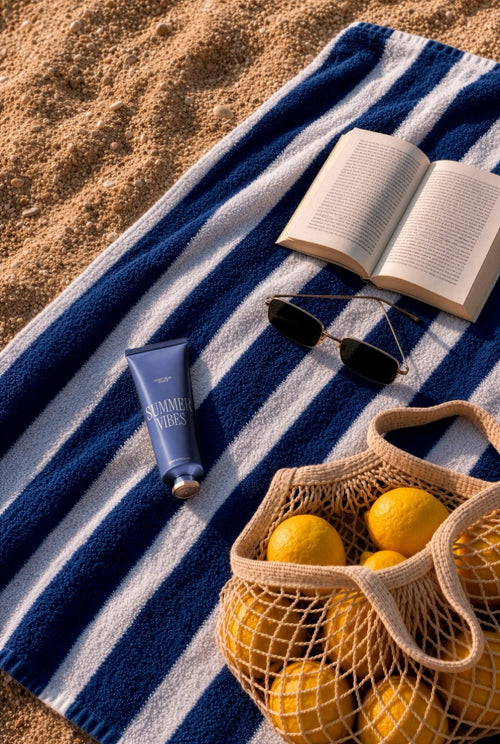 Hand cream tube mockup PSD on a striped beach towel with sunglasses, a book, and lemons