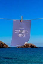 Print poster mockup PSD hanging from a clothesline over the ocean with a rocky coastline