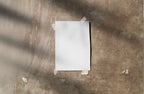 Real photo taped print poster mockup on textured wall with natural shadows (paper grain visible)