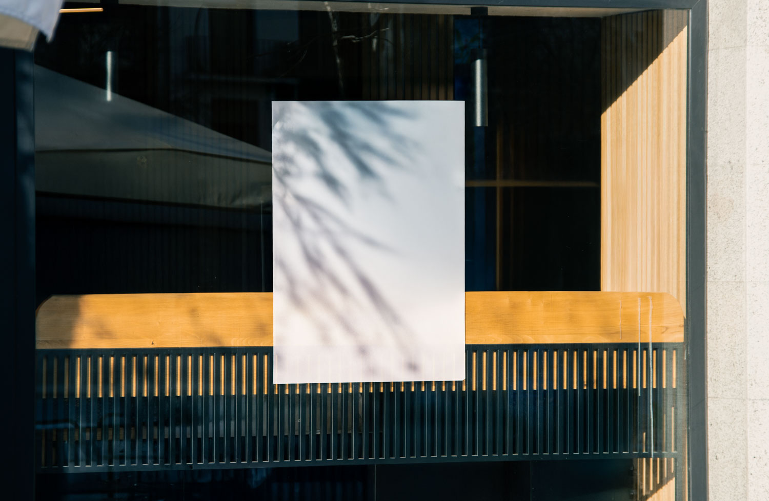 Real photo window poster mockup PSD on shop glass with natural reflections and wood interior
