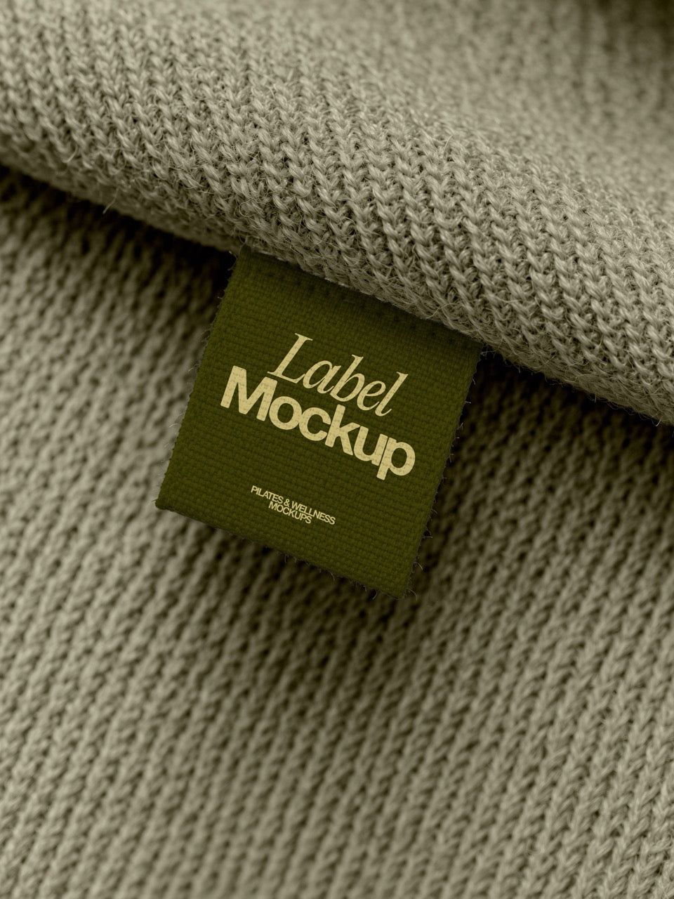 Woven label mockup in olive sewn into a sage knit sweater. Clothing label mockup for activewear and knitwear brands. Woven label mockup, clothing tag mockup, apparel label mockup, knitwear mockup, pilates mockup, apparel mockup, high quality mockup, PSD file.