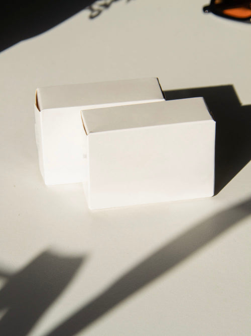 box packaging mockup PSD with two stacked paper boxes on sunlit desk and plant shadows