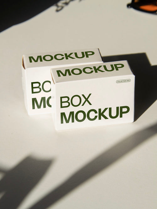 box packaging mockup PSD with two stacked paper boxes on sunlit desk and plant shadows