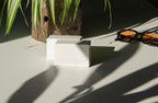 box packaging mockup PSD with three stacked paper boxes on sunlit desk and plant shadows