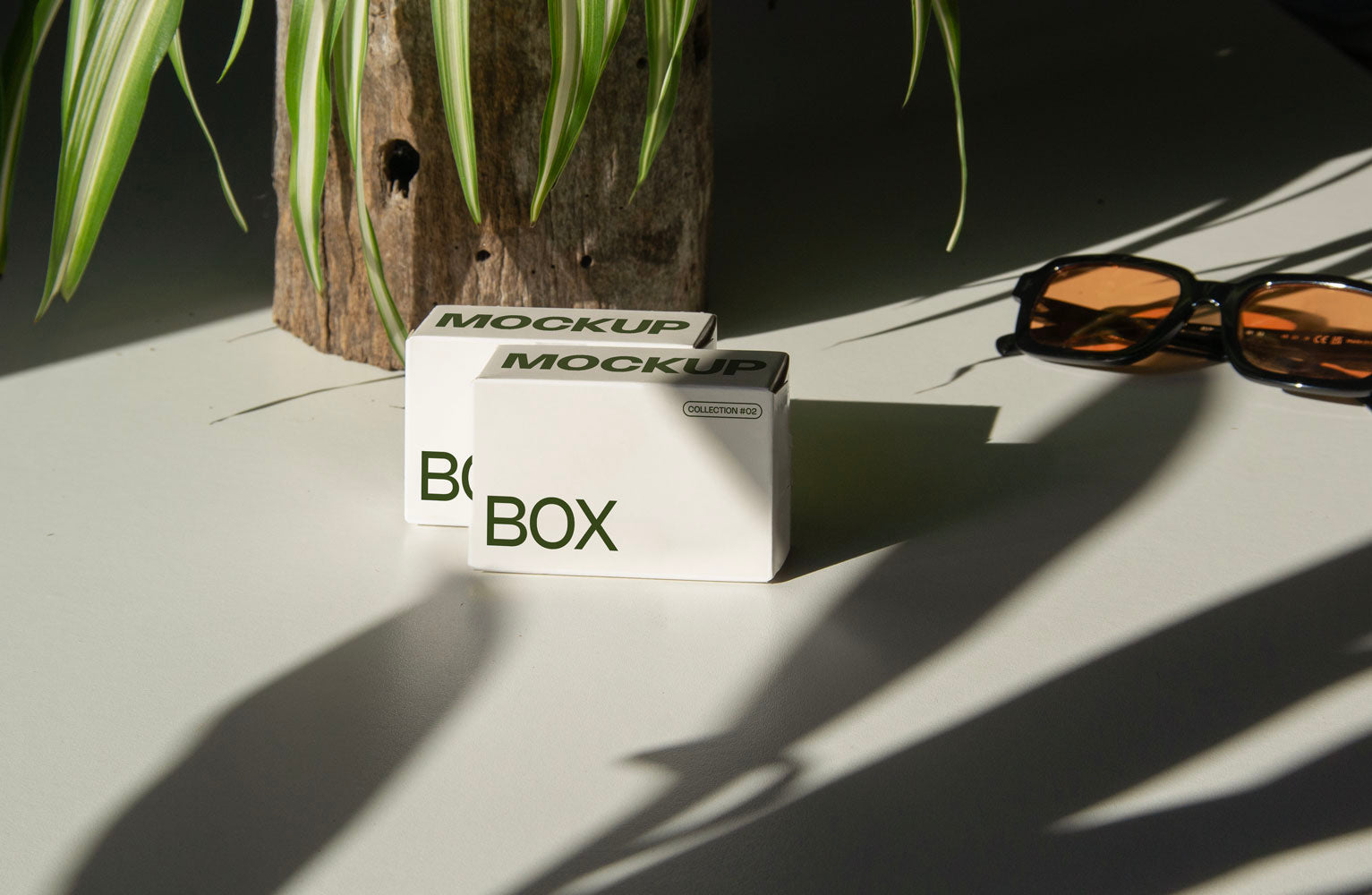 box packaging mockup PSD with three stacked paper boxes on sunlit desk and plant shadows