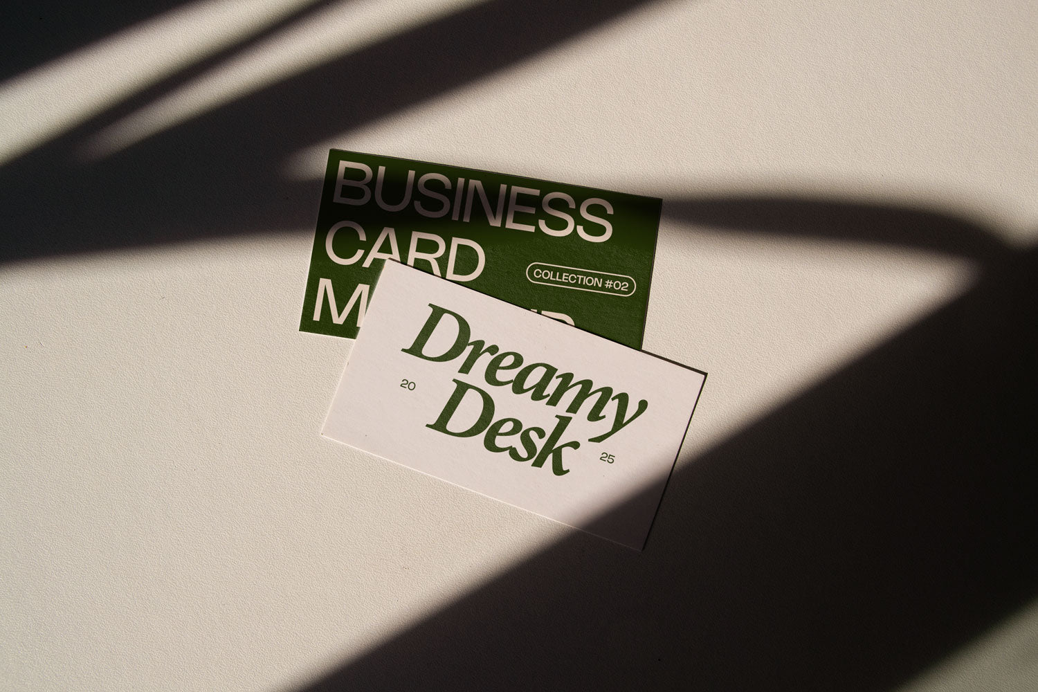 business card mockup PSD with two cards (portrait and landscape) on sunlit desk with plant shadows