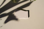 business card mockup PSD with two cards (portrait and landscape) on sunlit desk with plant shadows