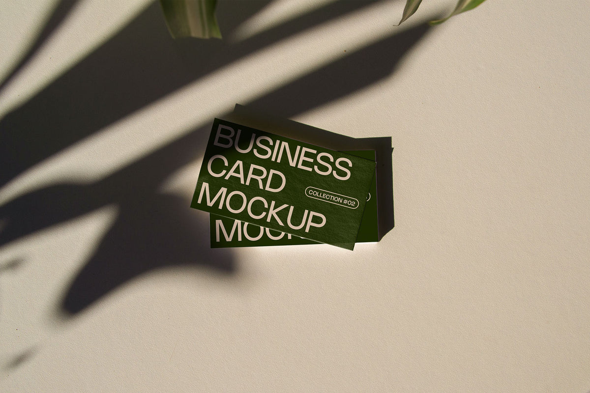 business card mockup PSD with two cards (portrait and landscape) on sunlit desk with plant shadows