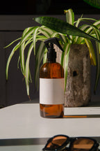 fabric spray bottle label mockup PSD on sunlit table with plant shadows and amber glass