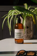 fabric spray bottle label mockup PSD on sunlit table with plant shadows and amber glass