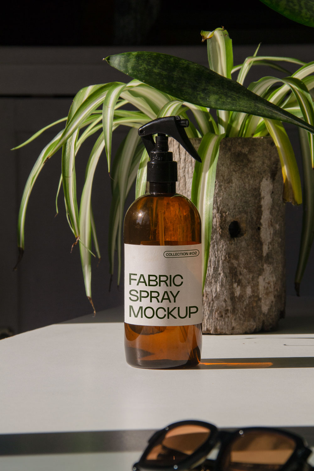fabric spray bottle label mockup PSD on sunlit table with plant shadows and amber glass