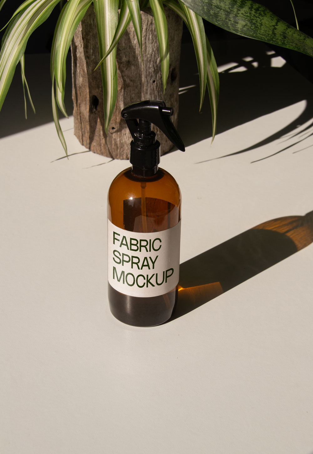 fabric spray bottle label mockup PSD on sunlit table with plant shadows and amber glass