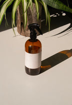 fabric spray bottle label mockup PSD on sunlit table with plant shadows and amber glass
