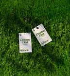 hang tag mockup PSD on grass with two clothing tags and black cord under natural light