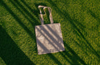 tote bag mockup PSD on sunlit grass with natural shadows and visible fabric texture