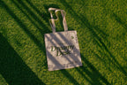 tote bag mockup PSD on sunlit grass with natural shadows and visible fabric texture