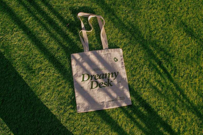 tote bag mockup PSD on sunlit grass with natural shadows and visible fabric texture