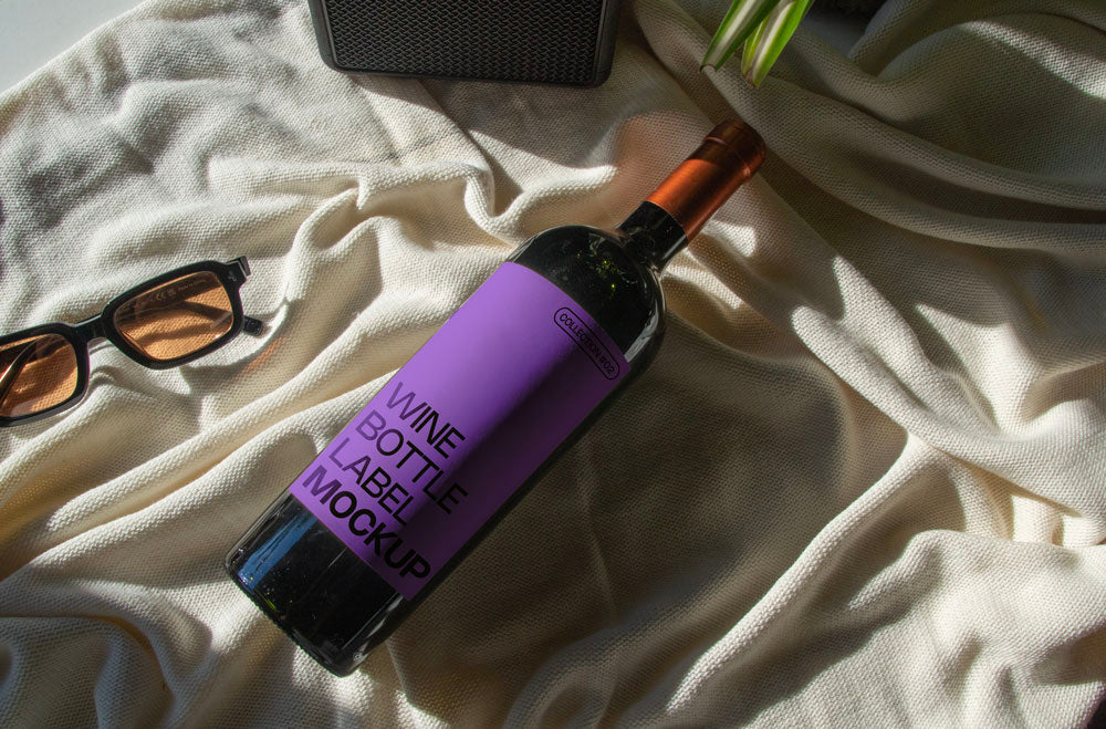 wine bottle label mockup PSD on sunlit table with plant shadows and glass reflections
