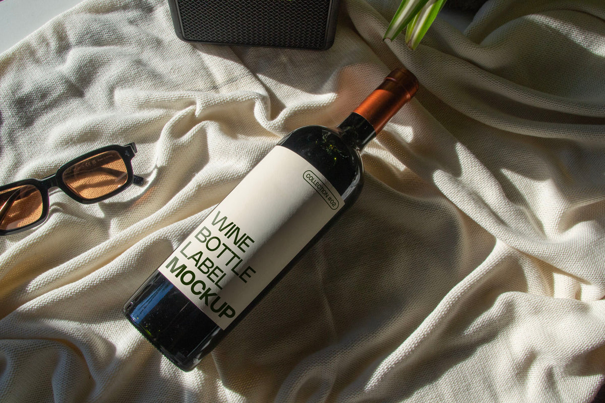 wine bottle label mockup PSD on sunlit table with plant shadows and glass reflections
