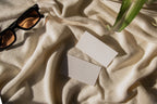 business card mockup PSD with two cards (portrait and landscape) on sunlit desk with plant shadows