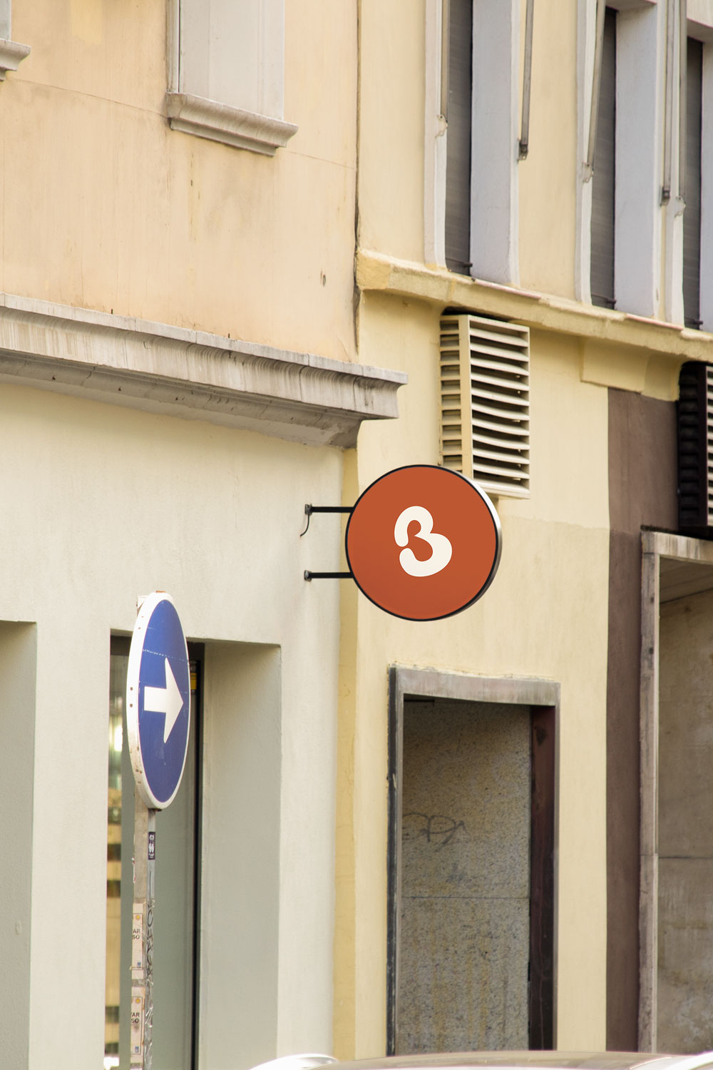 round storefront logo sign mockup PSD mounted on city building façade