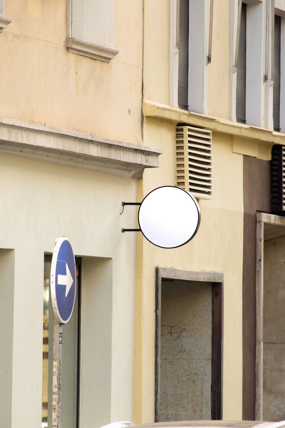 round storefront logo sign mockup PSD mounted on city building façade
